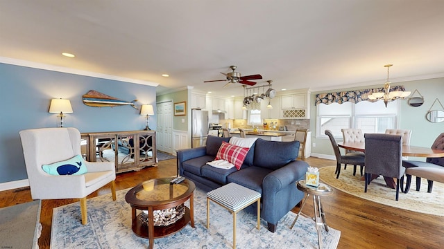 living room featuring ceiling fan with notable chandelier, ornamental molding, and light hardwood / wood-style floors