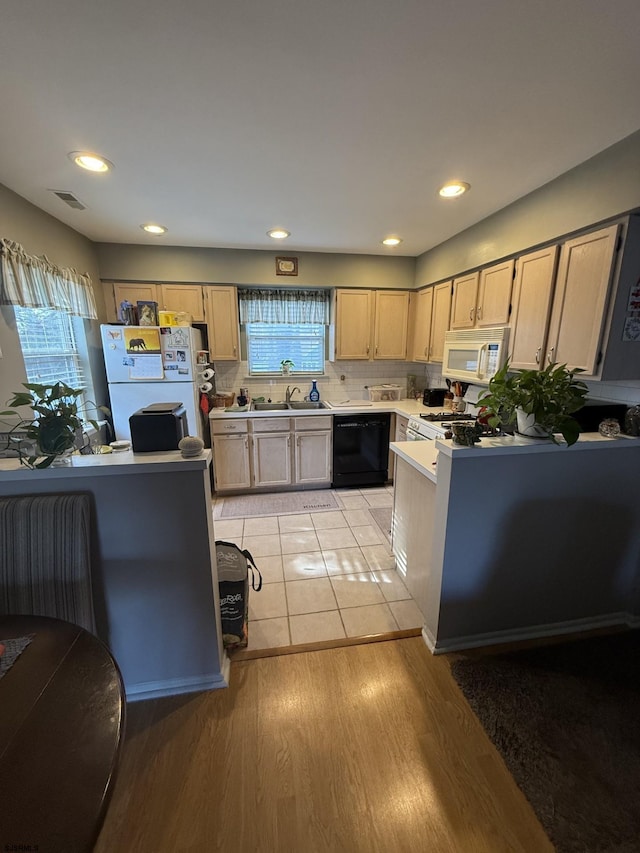 kitchen with light brown cabinetry, sink, light wood-type flooring, white appliances, and a healthy amount of sunlight