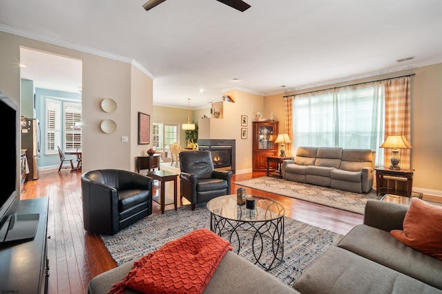 living room with wood-type flooring, ornamental molding, and a wealth of natural light