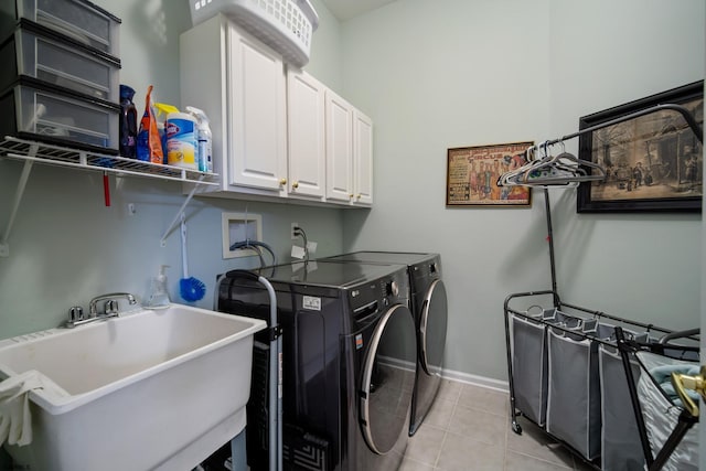 clothes washing area featuring cabinets, sink, light tile patterned floors, and washing machine and clothes dryer