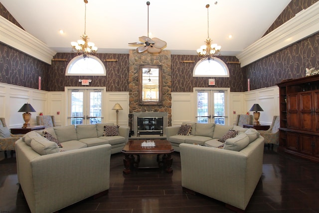 living room featuring french doors, an inviting chandelier, ornamental molding, dark hardwood / wood-style flooring, and a fireplace