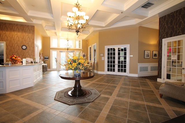 interior space with beam ceiling, a towering ceiling, coffered ceiling, french doors, and a chandelier