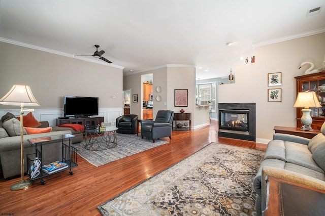 living room with ceiling fan, a multi sided fireplace, ornamental molding, and hardwood / wood-style floors