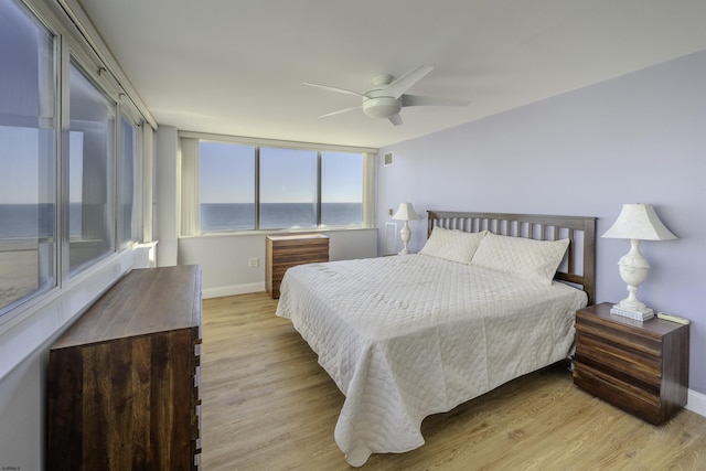 bedroom featuring a water view, ceiling fan, and light hardwood / wood-style flooring