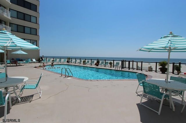 view of swimming pool with a water view and a patio area