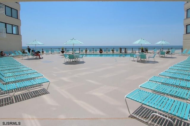 view of swimming pool with a water view and a view of the beach