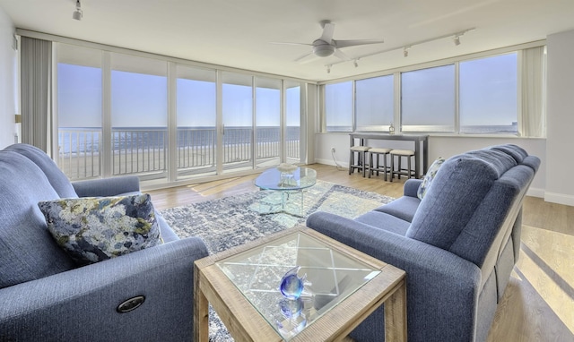 living room with a water view, a healthy amount of sunlight, hardwood / wood-style floors, and ceiling fan