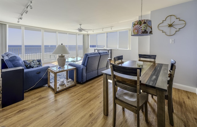 dining room featuring a water view, track lighting, wood-type flooring, and ceiling fan