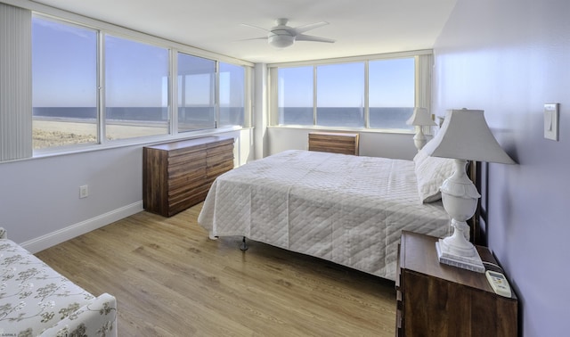 bedroom featuring a water view, light wood-type flooring, and ceiling fan