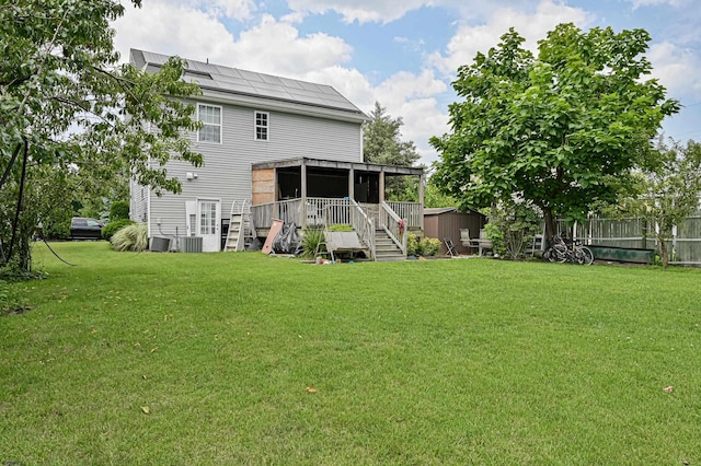 rear view of property with a yard, central air condition unit, a shed, and solar panels