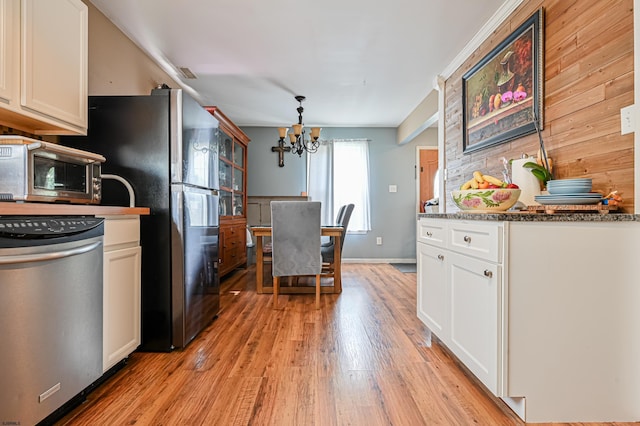 kitchen with white cabinetry, an inviting chandelier, black refrigerator, stone counters, and light hardwood / wood-style floors