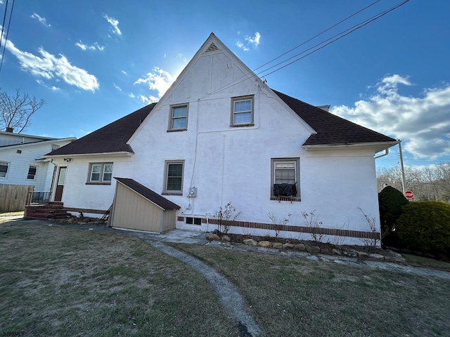 rear view of property featuring a shingled roof and a lawn