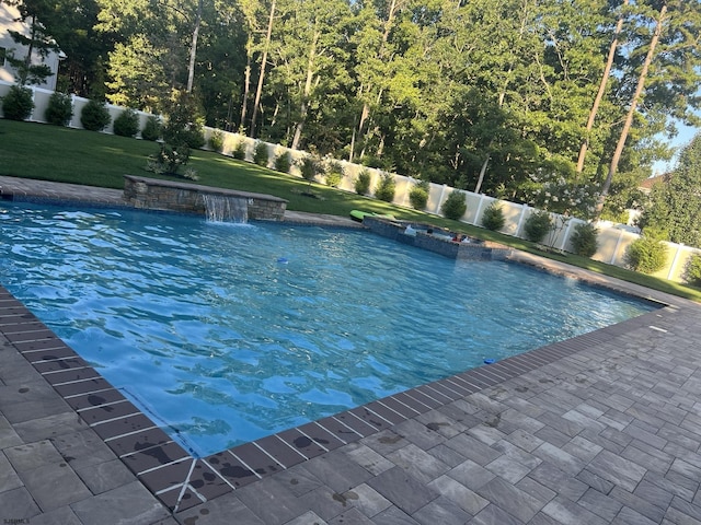 view of swimming pool featuring a hot tub, pool water feature, and a lawn