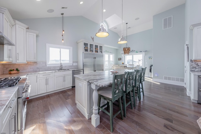 kitchen with high end appliances, sink, a kitchen island, and white cabinets