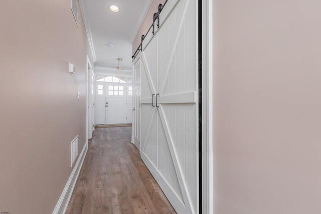 hall featuring crown molding, a barn door, and light wood-type flooring