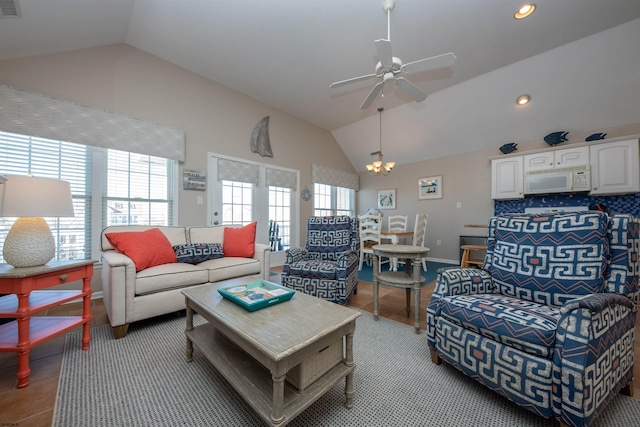 living room featuring ceiling fan with notable chandelier and vaulted ceiling