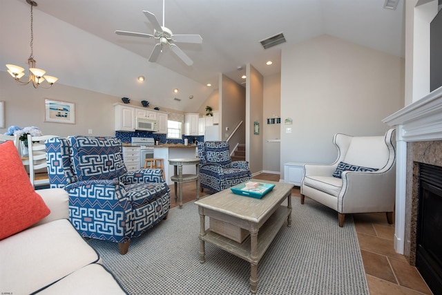 tiled living room featuring lofted ceiling, ceiling fan with notable chandelier, and a premium fireplace