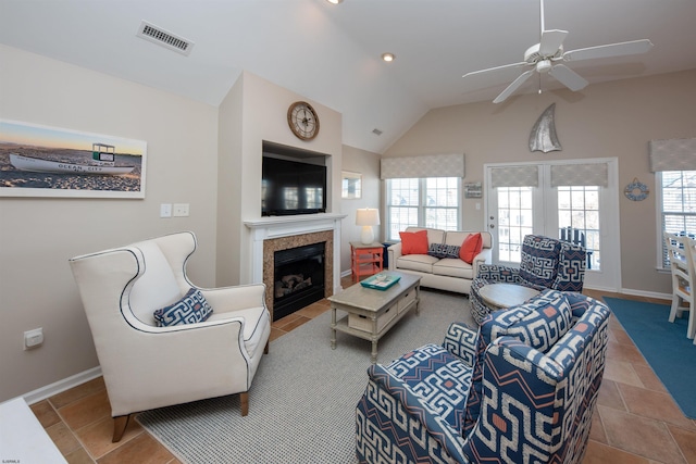 living room with a wealth of natural light, a tile fireplace, ceiling fan, and vaulted ceiling