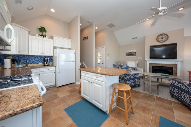 kitchen featuring white refrigerator, white cabinetry, lofted ceiling, and a center island