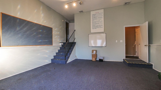 unfurnished living room featuring dark colored carpet and track lighting