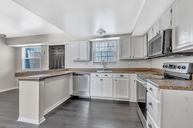 kitchen with dark hardwood / wood-style floors, white cabinetry, sink, kitchen peninsula, and stainless steel appliances