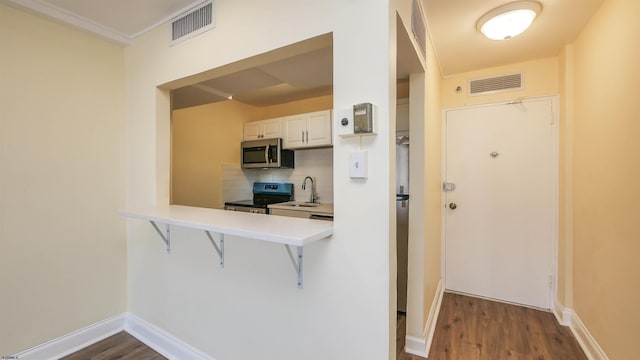 kitchen with tasteful backsplash, dark hardwood / wood-style flooring, stainless steel appliances, and white cabinets