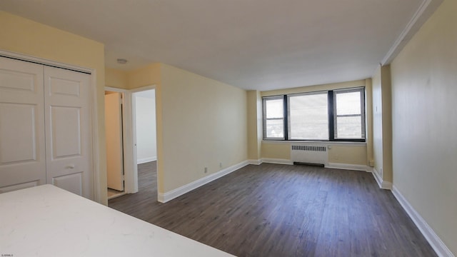 unfurnished bedroom with dark hardwood / wood-style flooring, radiator, and a closet