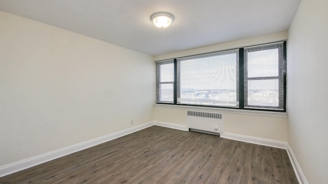 empty room featuring dark wood-type flooring and radiator heating unit