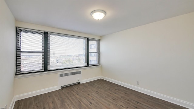 unfurnished room featuring radiator heating unit and dark hardwood / wood-style floors