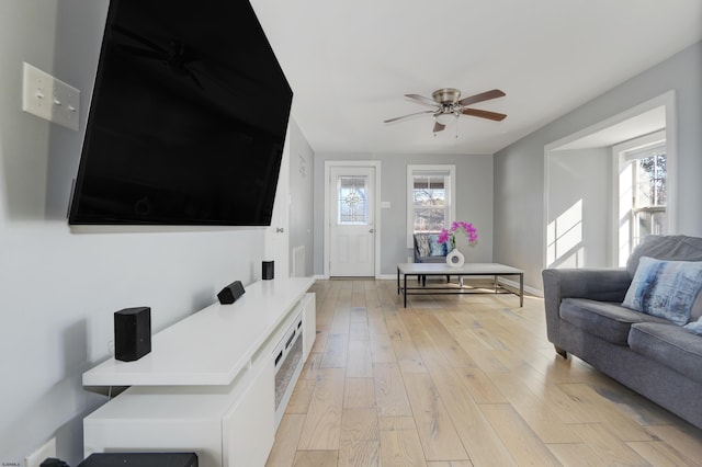 living room featuring ceiling fan, light hardwood / wood-style floors, and a wealth of natural light