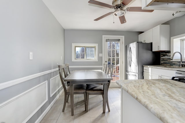 kitchen featuring light tile patterned flooring, sink, stainless steel fridge, white cabinets, and backsplash