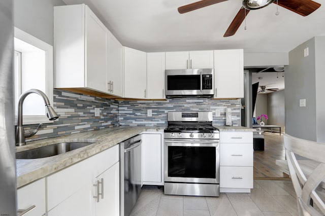 kitchen with white cabinetry, appliances with stainless steel finishes, sink, and light stone counters