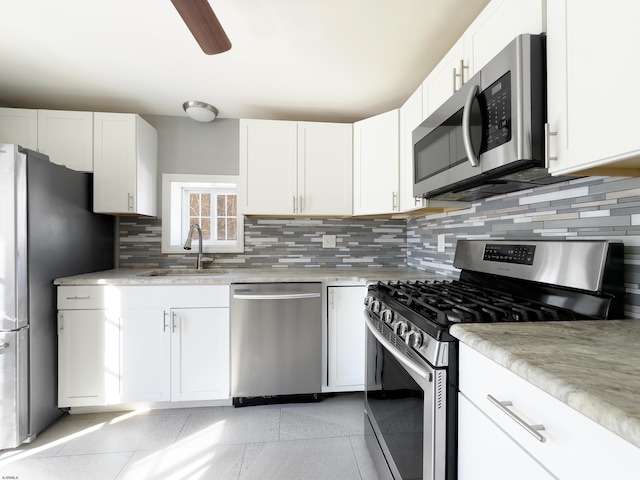 kitchen with sink, ceiling fan, appliances with stainless steel finishes, white cabinetry, and backsplash