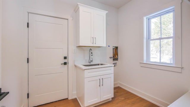 interior space with white cabinetry, sink, and light wood-type flooring