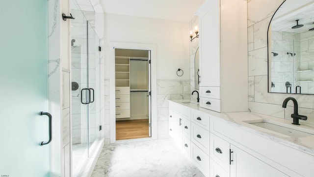 bathroom with tile walls, an enclosed shower, and vanity