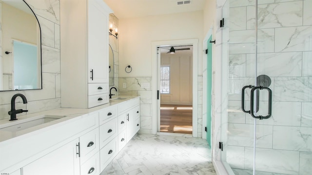 bathroom featuring vanity, a shower with shower door, and tile walls