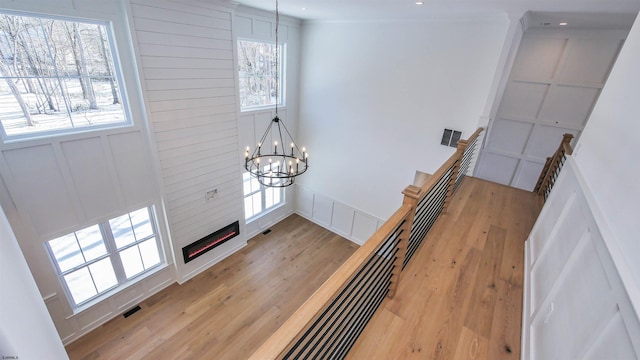 stairs with hardwood / wood-style flooring, a large fireplace, a wealth of natural light, and an inviting chandelier