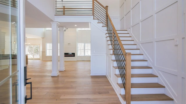 staircase featuring ornate columns, a high ceiling, and hardwood / wood-style floors