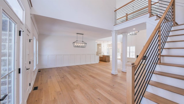 entryway featuring sink, light hardwood / wood-style flooring, a notable chandelier, decorative columns, and a high ceiling