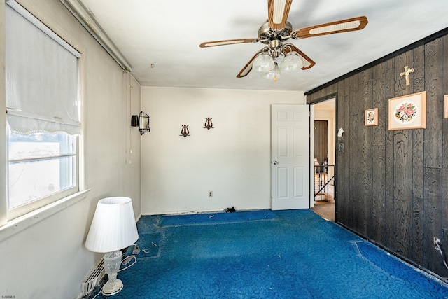 spare room with carpet floors, wooden walls, and ceiling fan