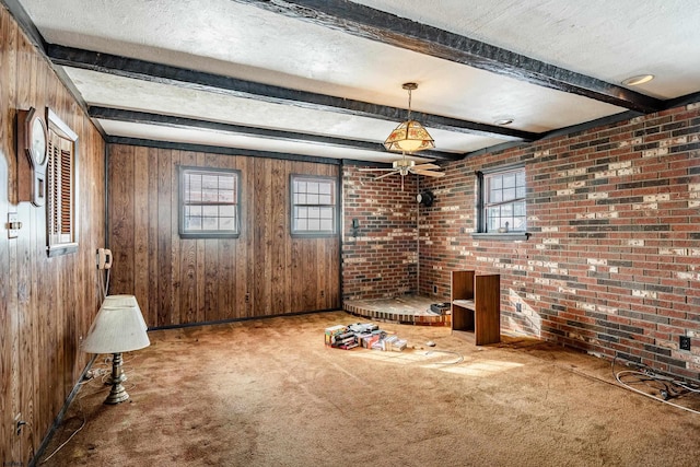 unfurnished living room featuring beamed ceiling, wooden walls, a textured ceiling, and carpet