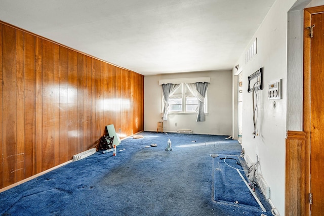 carpeted spare room with wood walls