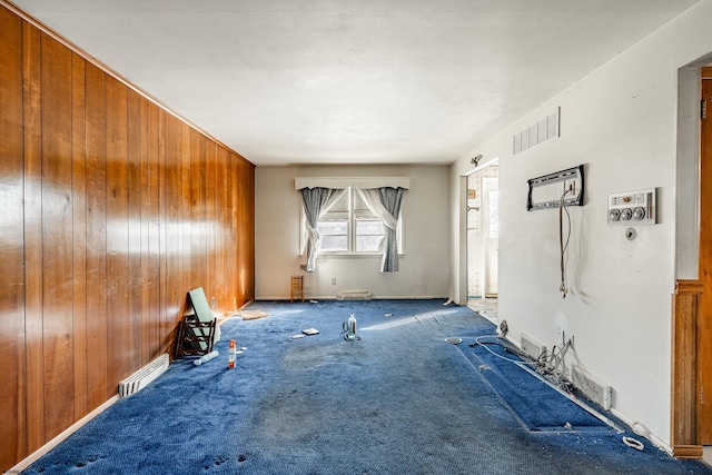 spare room featuring carpet and wood walls