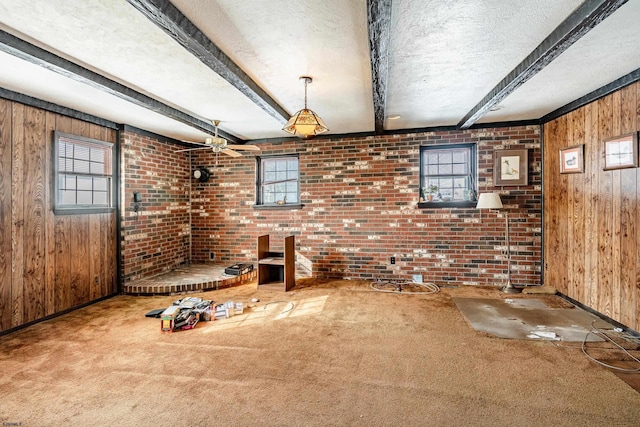 unfurnished living room featuring carpet, beamed ceiling, and wood walls