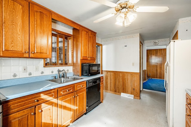 kitchen featuring sink, wooden walls, ceiling fan, decorative backsplash, and black appliances