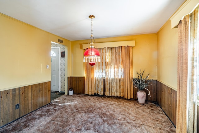 carpeted dining area featuring ornamental molding and wood walls