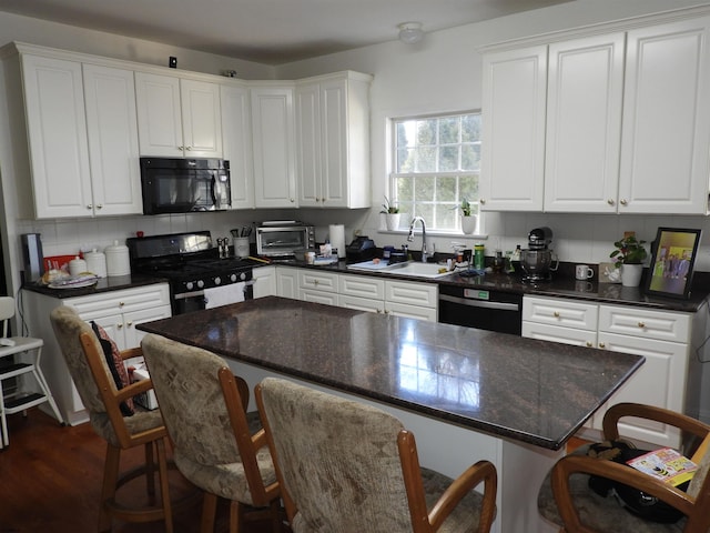 kitchen with sink, black appliances, a breakfast bar, and white cabinets