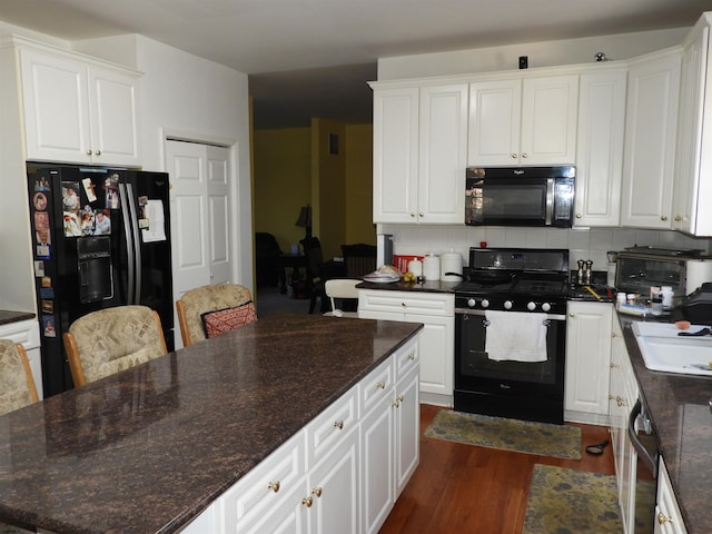 kitchen featuring white cabinetry, tasteful backsplash, dark stone countertops, dark hardwood / wood-style flooring, and black appliances