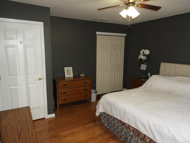 bedroom with wood-type flooring, ceiling fan, and a closet