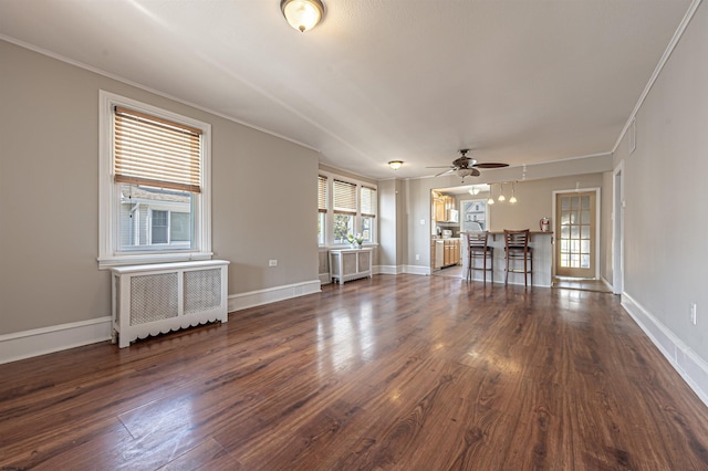 unfurnished living room featuring crown molding, dark hardwood / wood-style floors, radiator heating unit, and ceiling fan